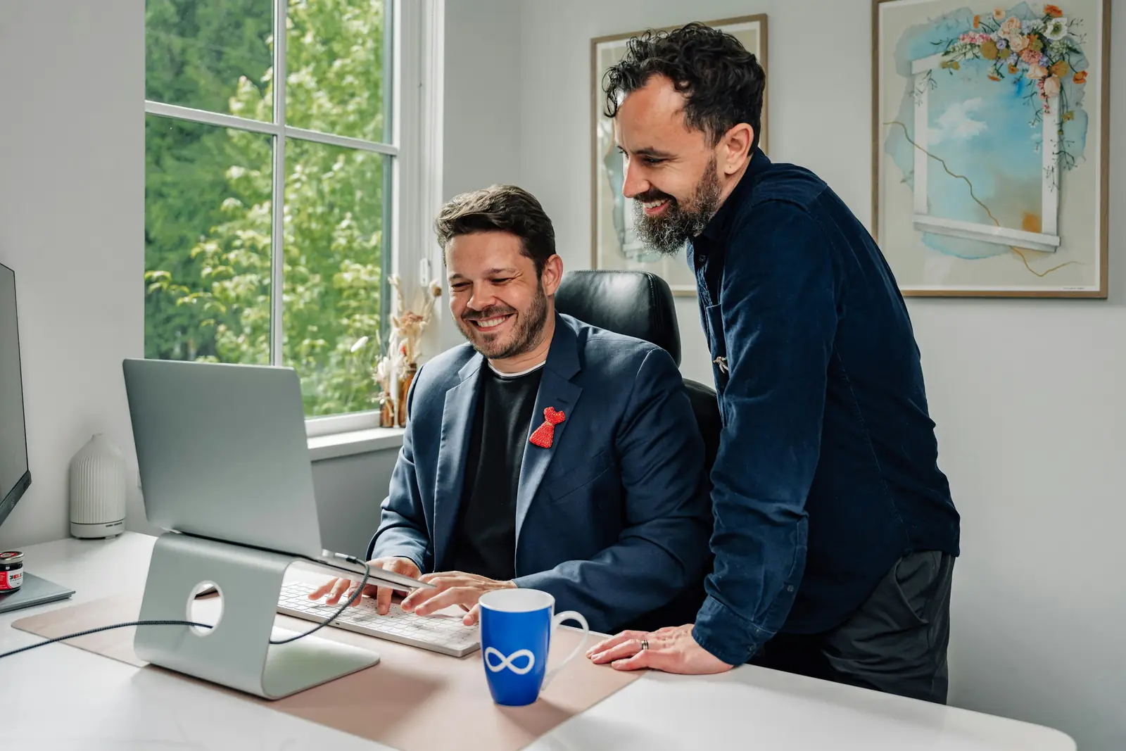 Two IT specialists smiling at a laptop in a bright office